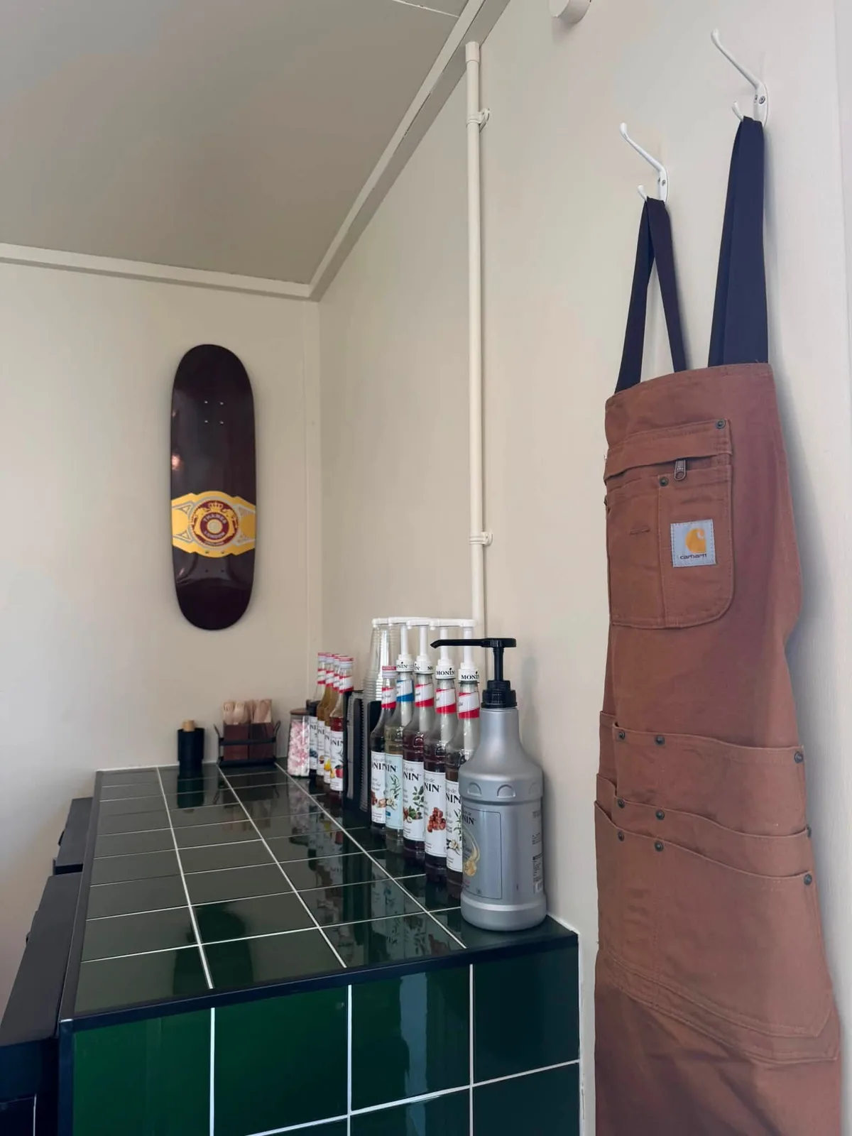 The green tiled counter, syrup bottles and a skate deck hung on the wall