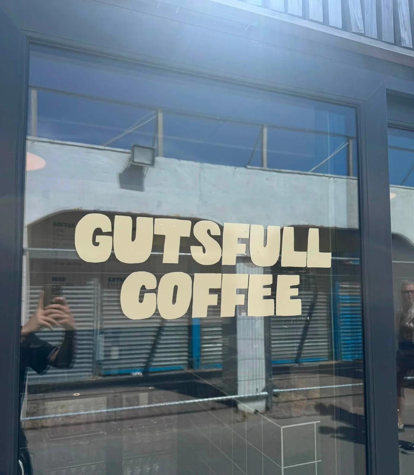 The Gutsfull Coffee wordmark in cream vinyl across the shop window